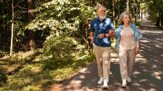 Casal maduro a caminhar num trilho natural, símbolo de vitalidade e saúde cardiovascular com apoio natural.