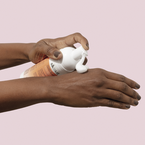Espuma de Limpeza Nutritiva Skin.q – oBoticário, frasco branco e laranja aplicado nas mãos, textura leve e cremosa com Ácido Hialurónico e Goji Berry.