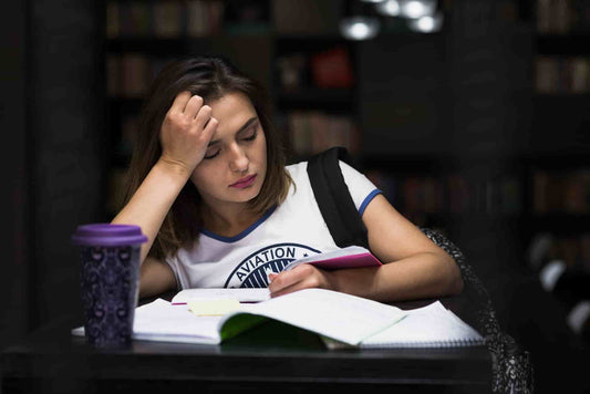 Estudante com dificuldade de foco durante a época de exames, ilustrando a falta de concentração nos estudos.
