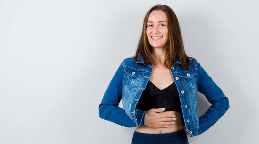 Mulher sorridente com a mão no estômago, transmitindo conforto digestivo após refeição, associada ao suplemento MEINENZIM