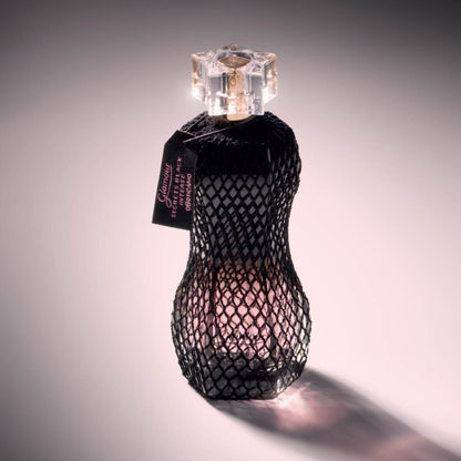Perfume Glamour Secrets Black Intense 75ml do Boticário, com frasco em formato curvo protegido por rede preta, iluminado em fundo suave.