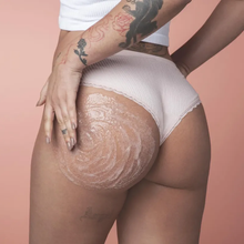 Aplicação do Creme Esfoliante Bumbum de Pêssego – oBoticário, textura cremosa com grãos esfoliantes sobre a pele, mostrando o modo de uso no corpo.